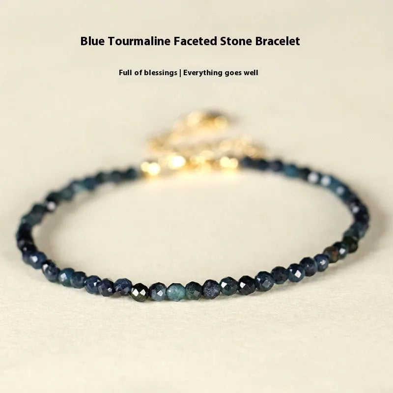Close-up of a blue tourmaline beaded bracelet with metallic spacer beads on a woman's wrist.