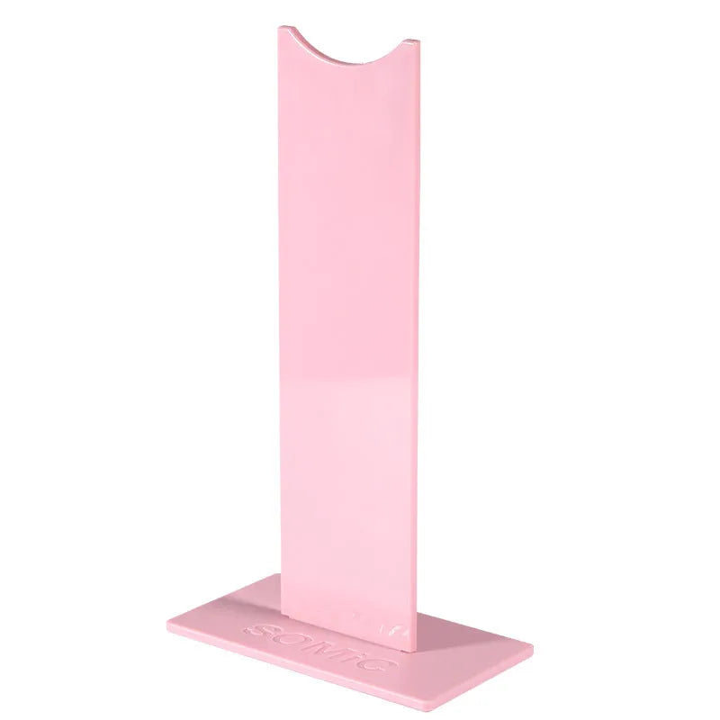A black or pink detachable headphone stand for head-mounted gaming headsets on a desk.
