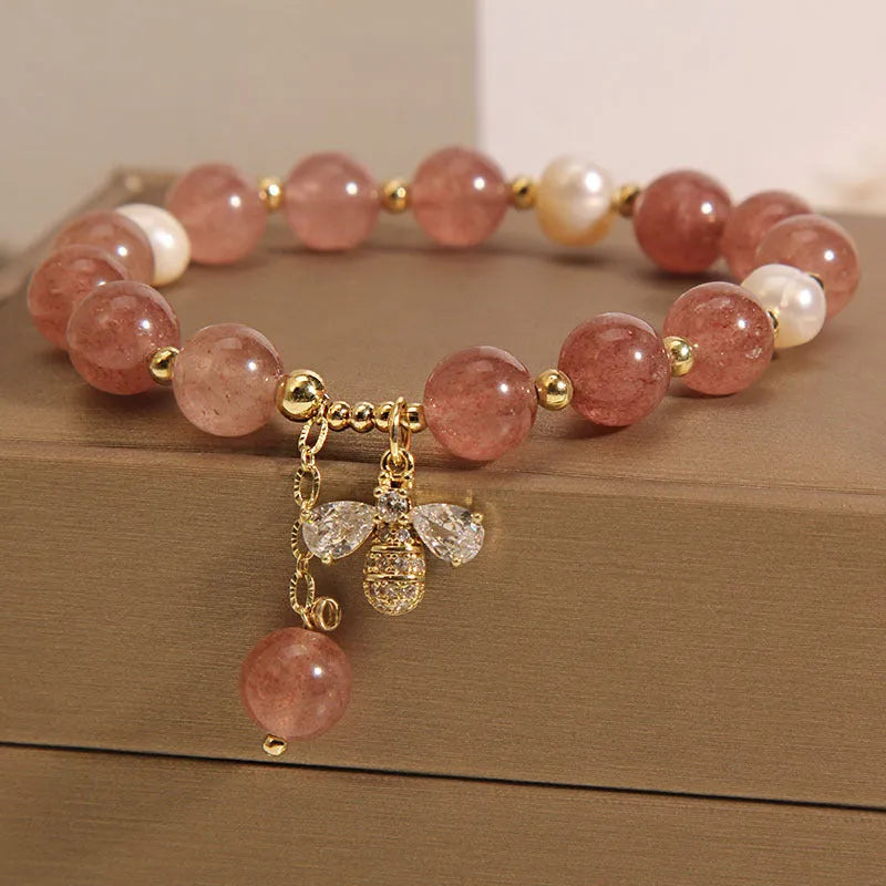 Close-up of a women's bracelet with pink strawberry quartz stones, white freshwater pearls, and sparkling zircon accents on an alloy clasp.