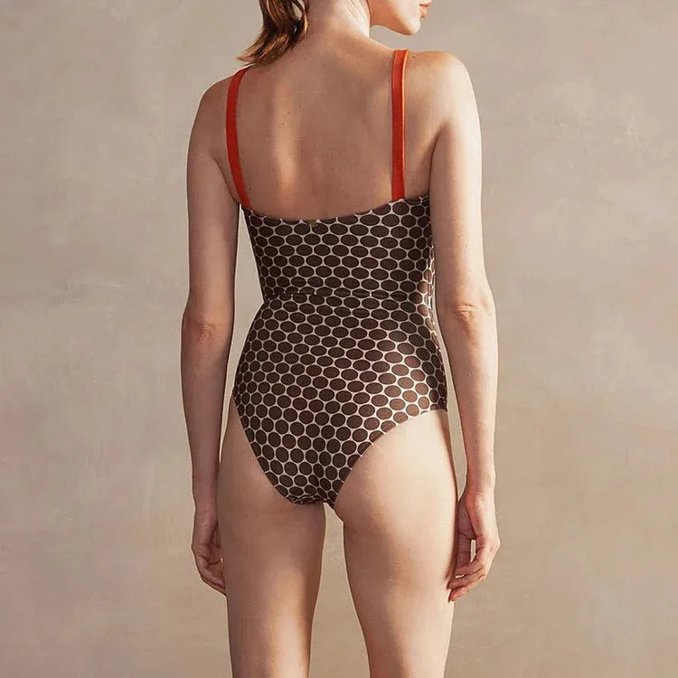 Women's dotted one-piece swimsuit with a matching wrap skirt laid flat.