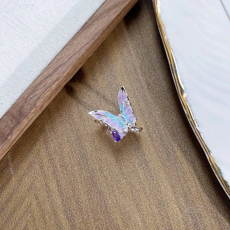 Adjustable copper ring with insect motif and colourful drip-oil finish in hand.