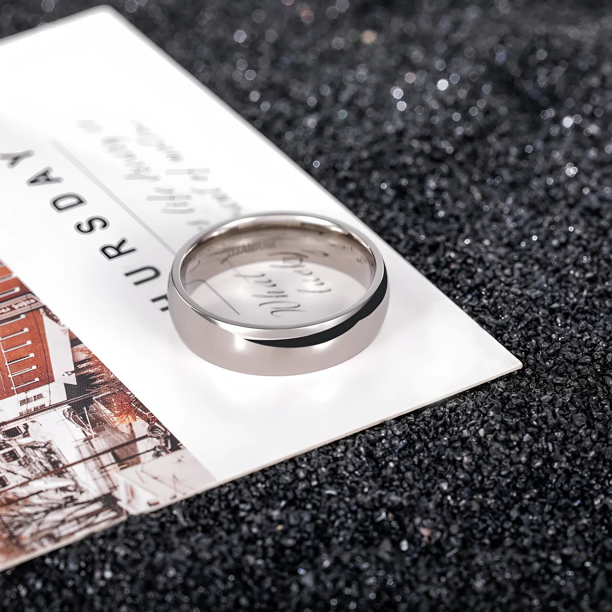 Silver titanium steel ring on a plain background showing its simple band design and grinding finish
