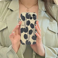 Black silicone iPhone case with tulip flower design shown on mobile phone
