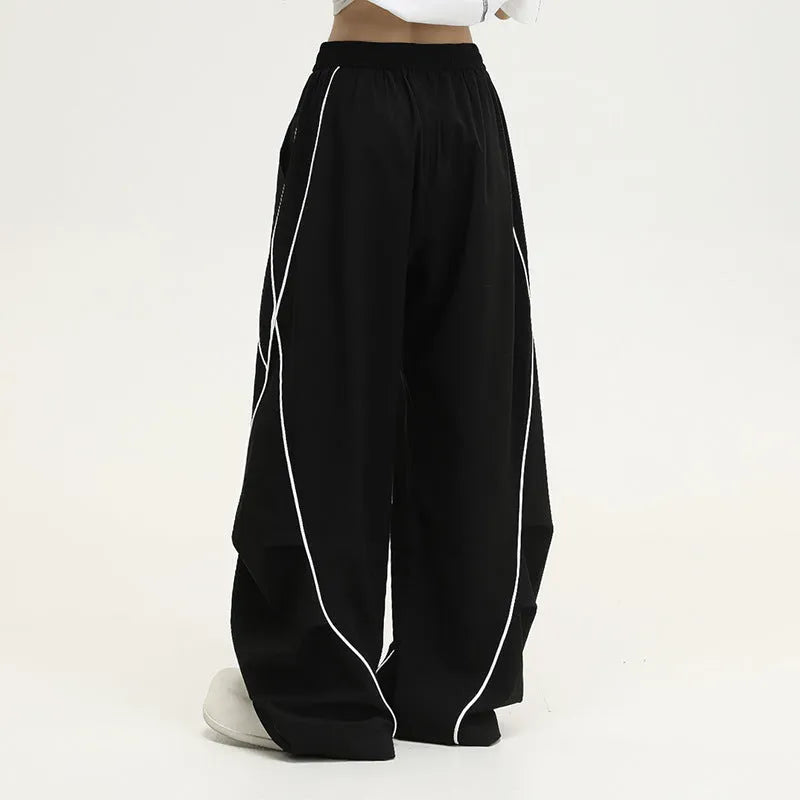 Black pleated wide-leg trousers with stripe pattern showing loose fit and mid waist design