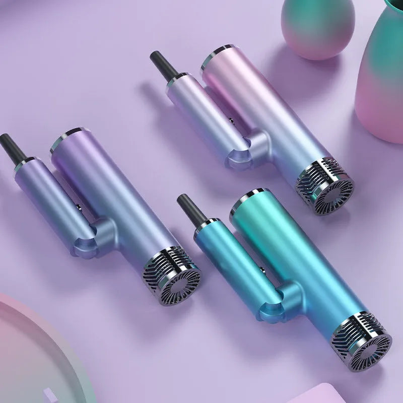 Green and purple foldable hair dryer with collapsed handle next to a suitcase, showing its compact travel size.