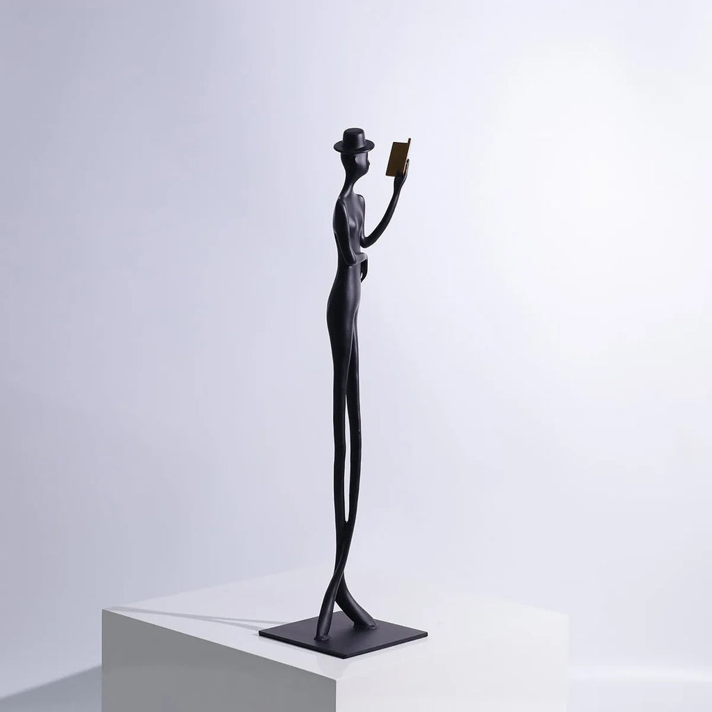Black cast aluminium sculpture of a woman reading, modern minimalist style.