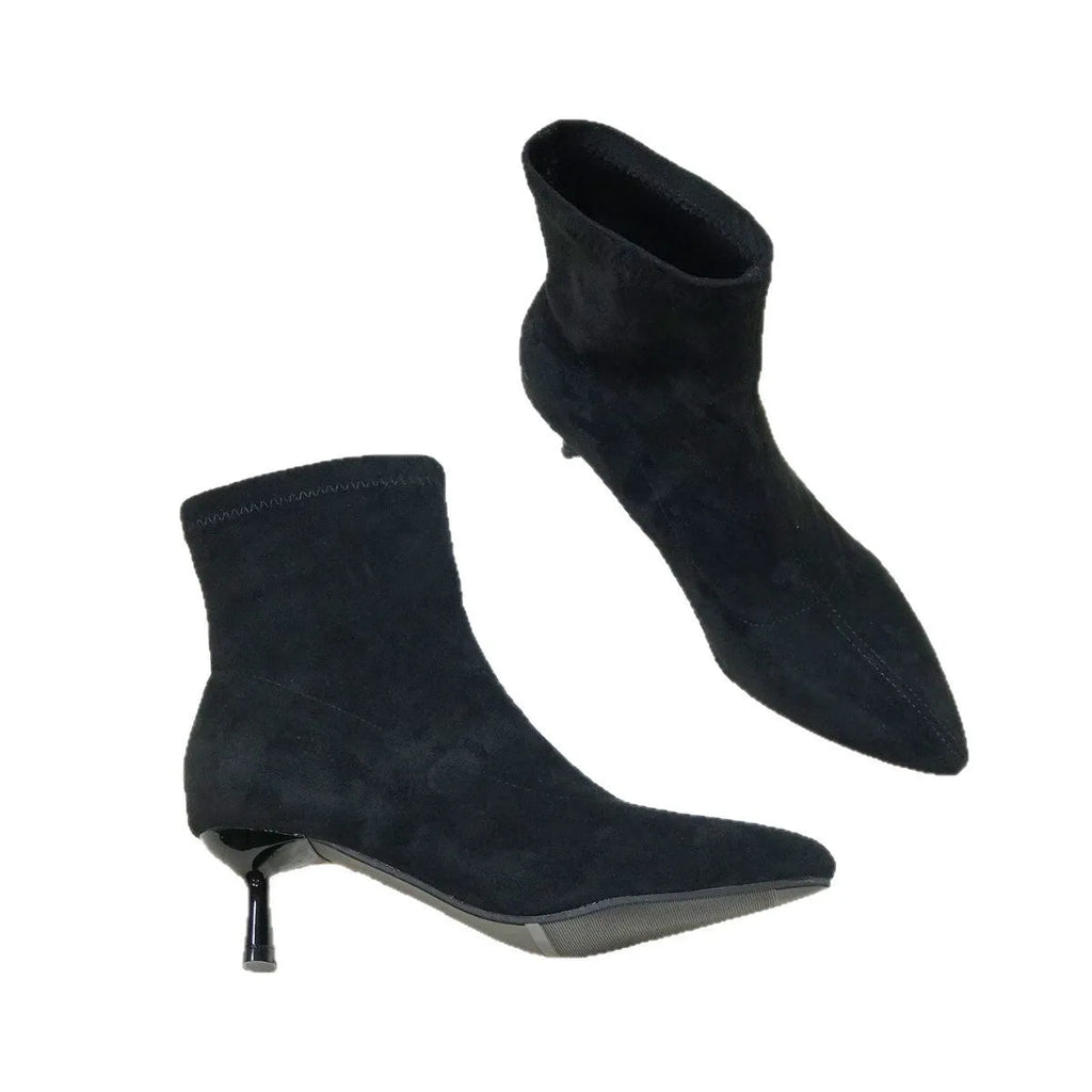 Women's black pointed toe ankle boots with stiletto heel on a plain background