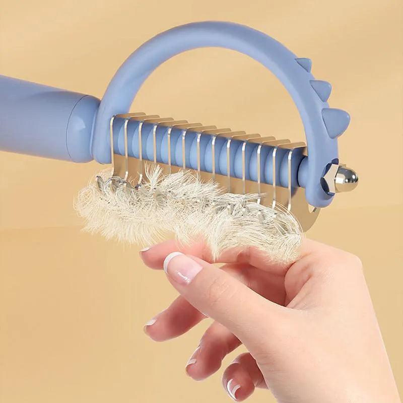 Blue dinosaur-shaped cat brush with self-cleaning button and stainless steel pins