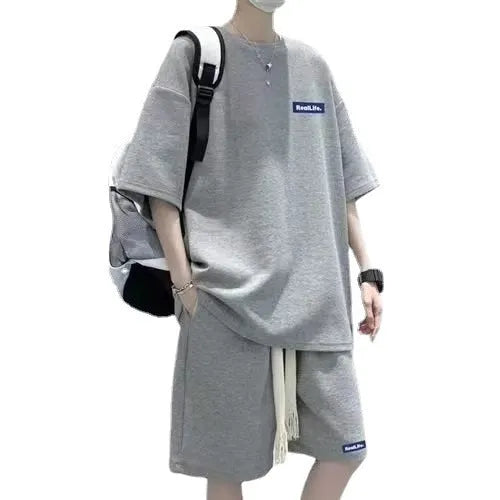 Man wearing a waffle-textured grey short sleeve top and matching shorts from a leisure sports suit set.