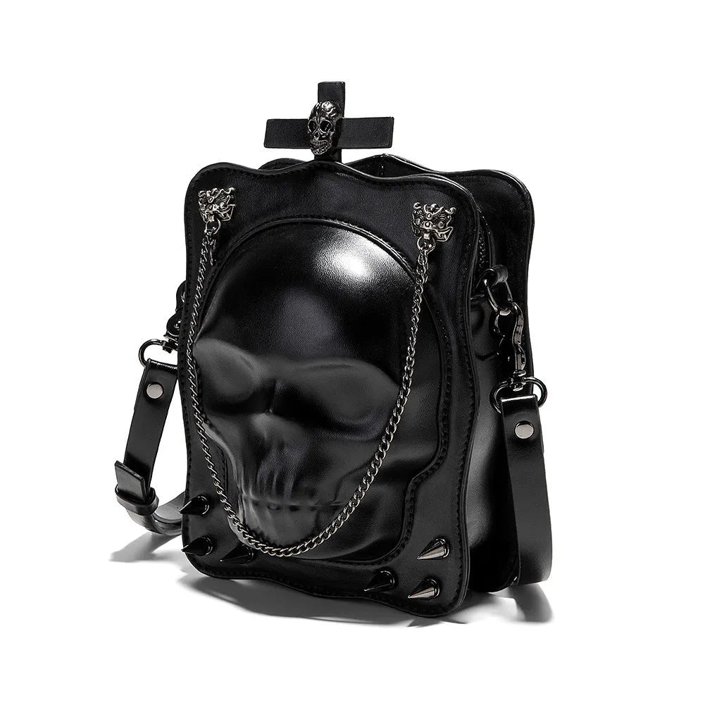 Black mini square crossbody bag with embossed skull design, metal chain strap, rivets, and contrast stitching.