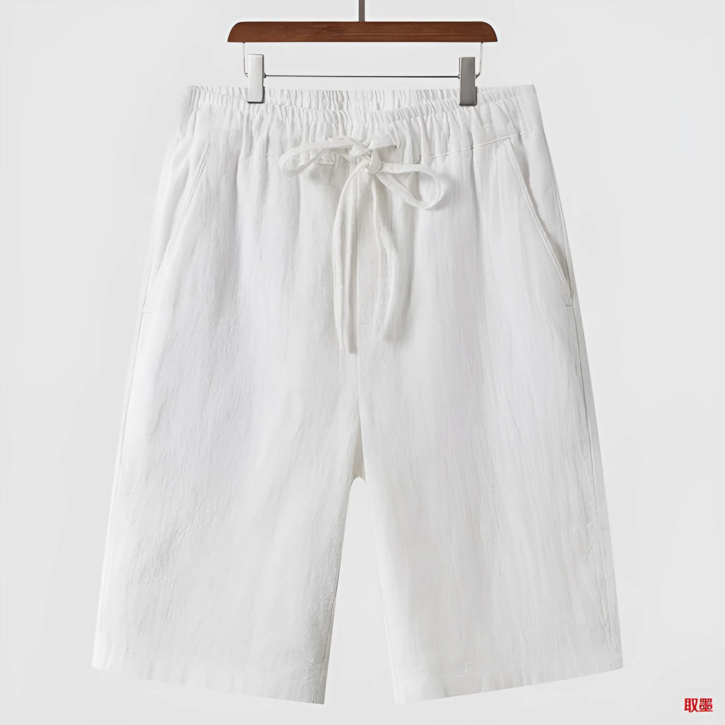 A pair of beige linen shorts for men with a loose, cropped fit and a mid-rise elasticated waistband.