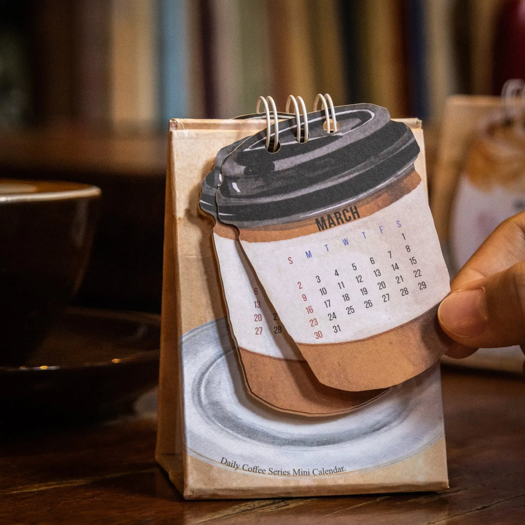 Coffee themed mini desk calendar for 2025 showing four different model designs on a desk.