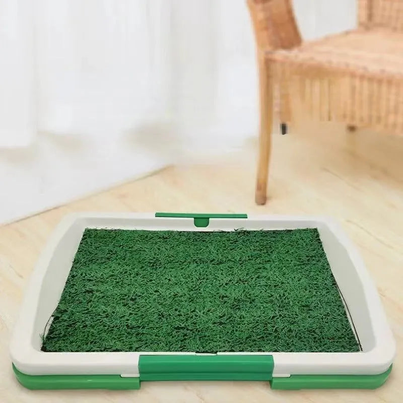 Green three-layer indoor dog toilet tray with artificial grass top, absorbent pad, and plastic drip tray base.