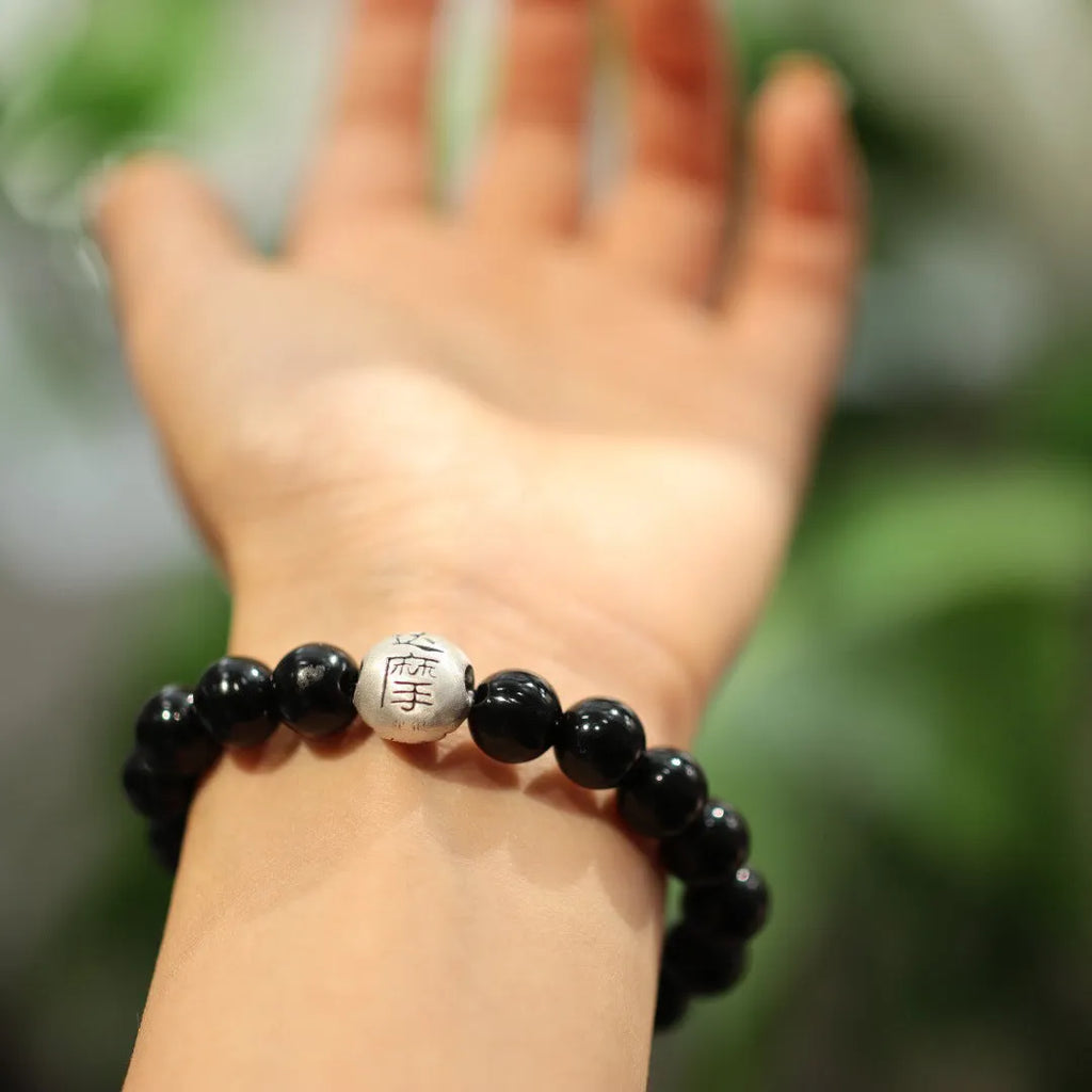 Close-up of a black agate and sterling silver bracelet with 10mm beads and a manual polish finish.