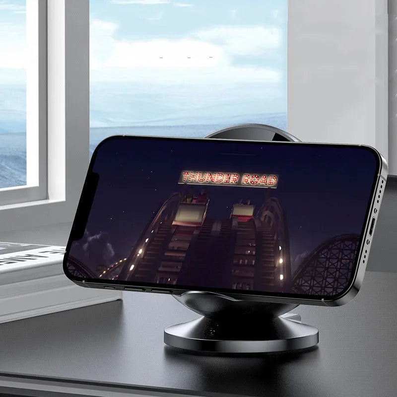 Black ABS plastic wireless phone charger holder with integrated Bluetooth speaker on a wooden desk.