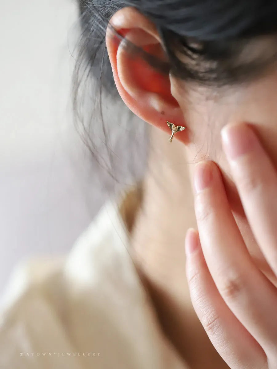 S925 sterling silver fishtail hoop earrings in gold colour on a white background.