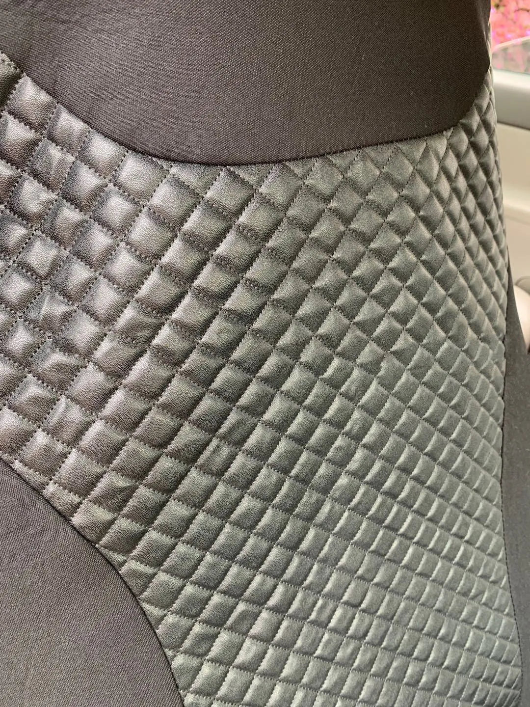 Black quilted car seat cover made from PU and polyester fabric with plastic installation hooks.