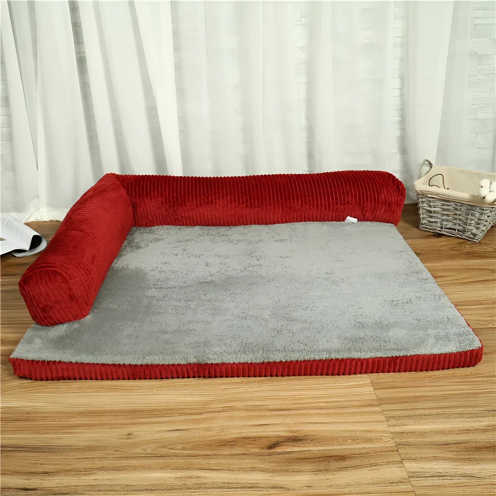 Corduroy dog sofa bed with bolster sides in a grey colour, shown on a wooden floor.