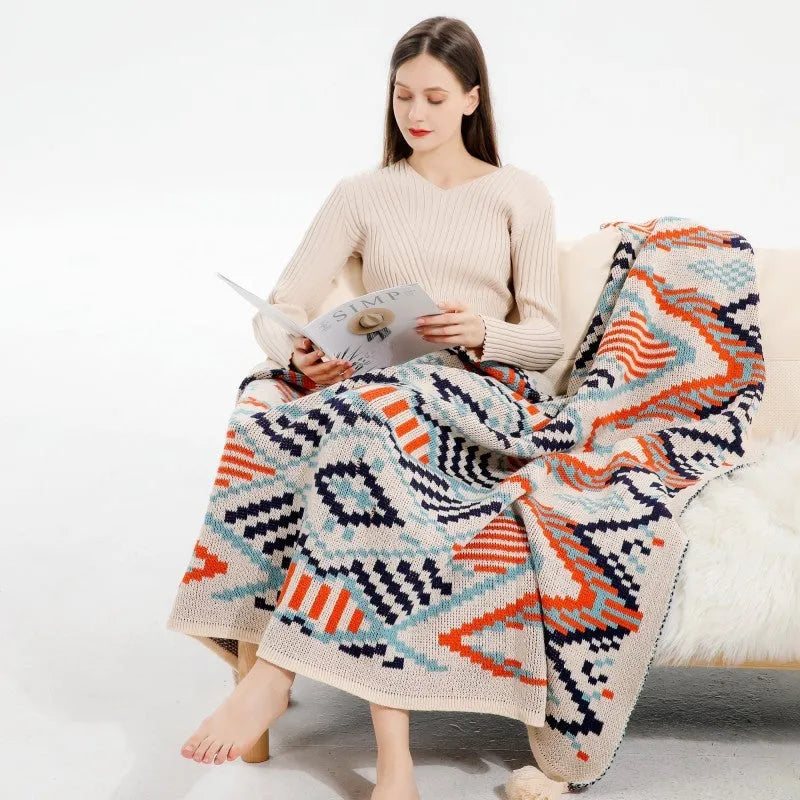 Bohemian style acrylic blanket with tassel fringe on a sofa, shown in a geometric print colour.