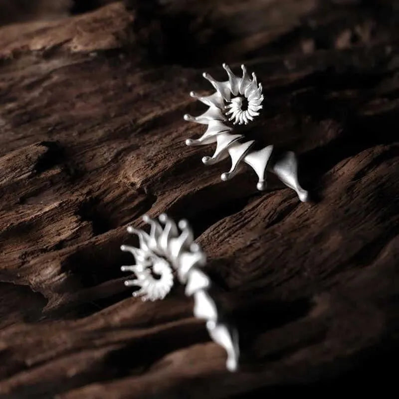 Close-up of a pair of matte-finish, three-dimensional conch shell stud earrings.