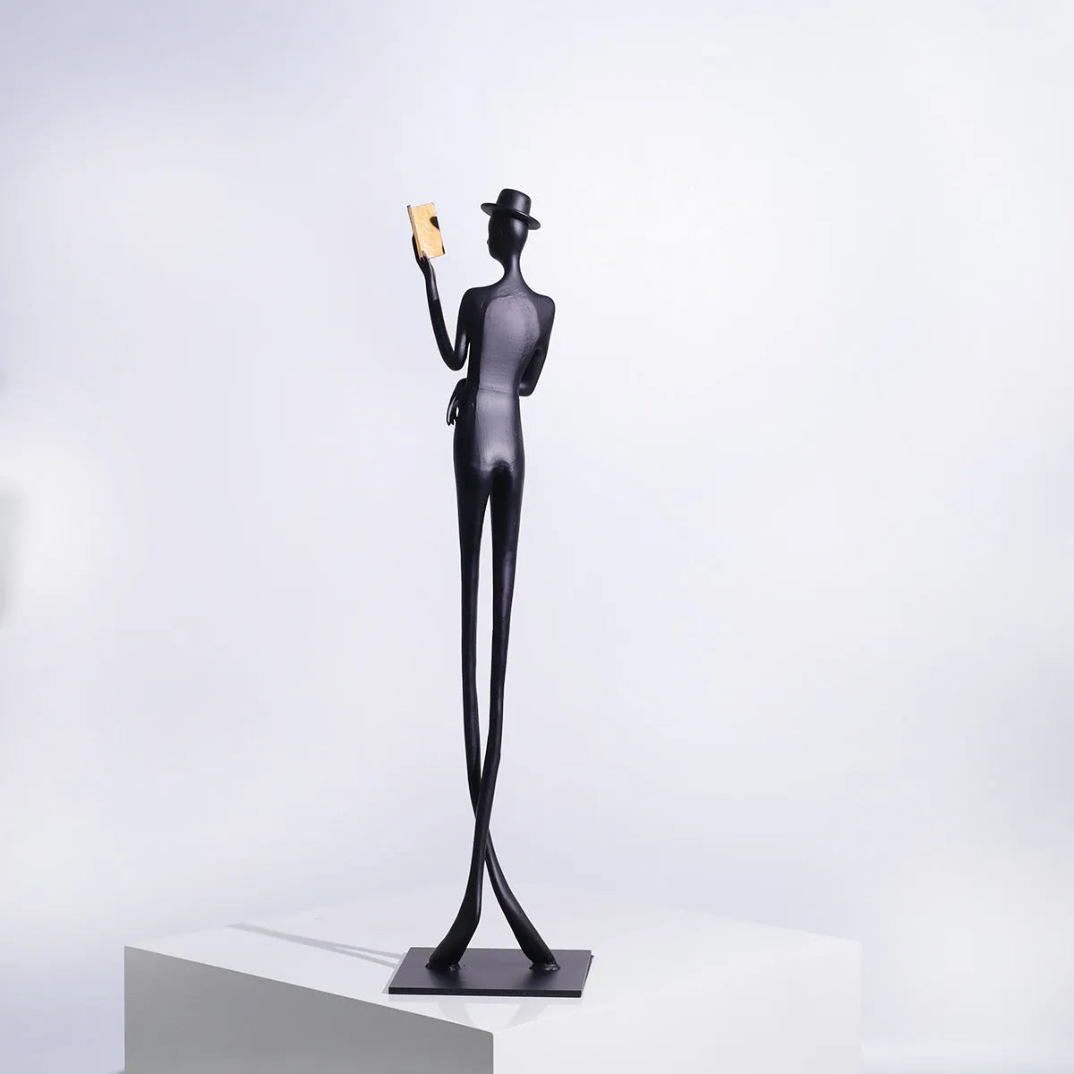 Black cast aluminium sculpture of a woman reading, modern minimalist style.