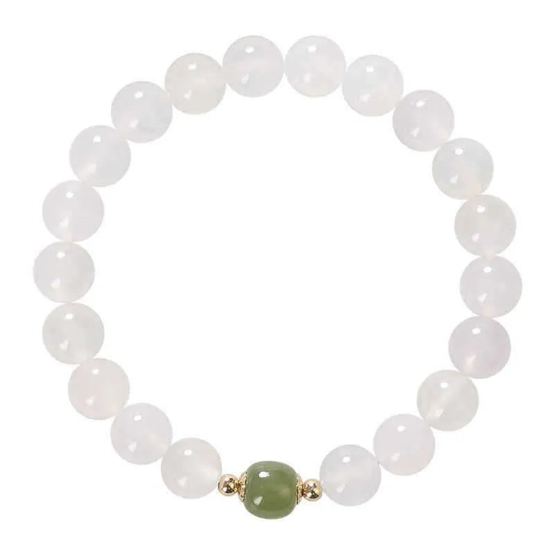Handmade white agate bracelet with red cinnabar letter inlays on a wrist.