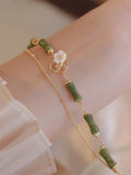 Handcrafted natural olivine bracelet with double layer design and twin Bells of Ireland charms.