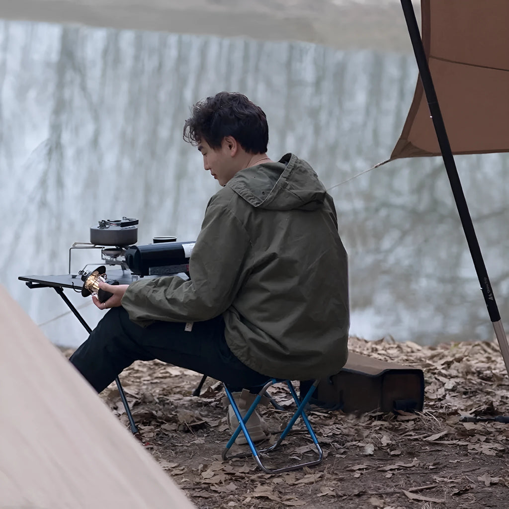 Black folding camping stool with an aluminium frame, shown in both open and folded positions.