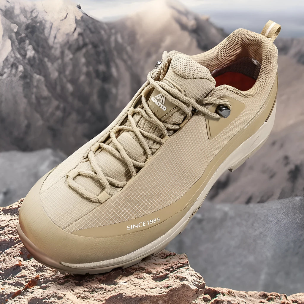 Men's low-top hiking boots in black with leather mesh upper and rubber outsole on a rocky path.