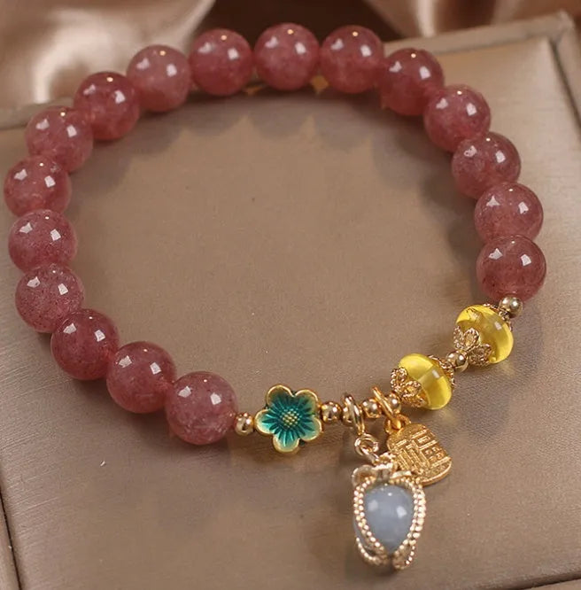 Red strawberry quartz beaded bracelet with silver-toned alloy charms and clear rhinestone details.