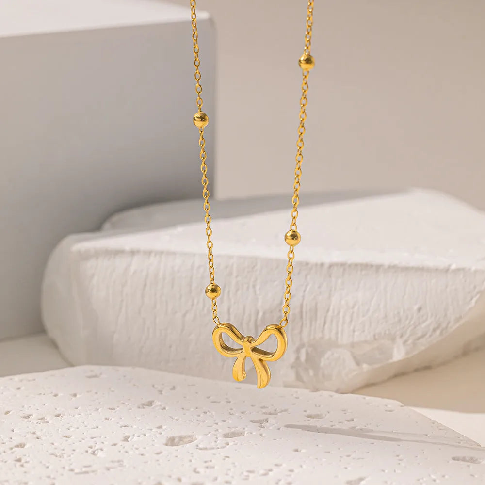 Gold-colour titanium steel necklace with a bow pendant on an adjustable chain