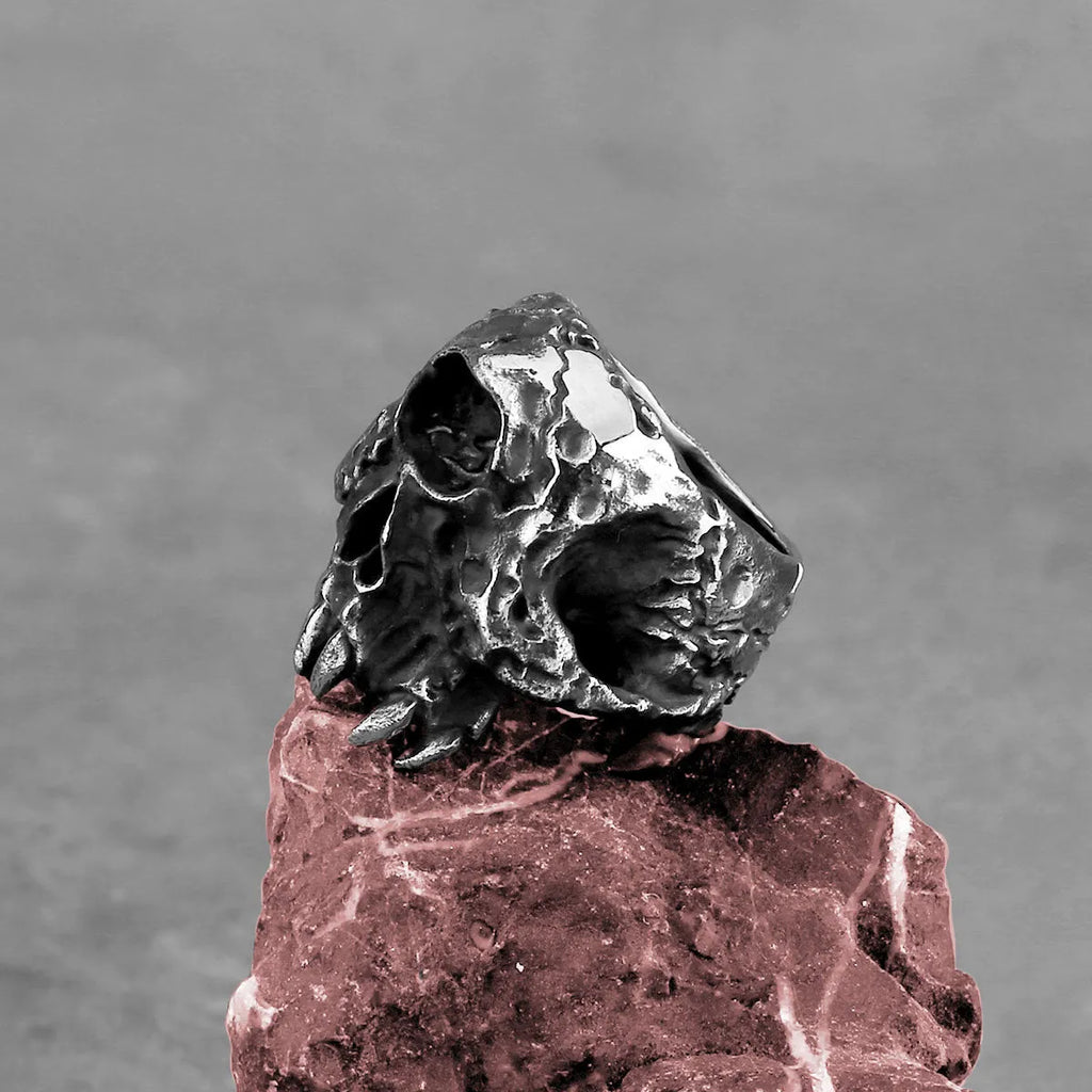 Silver-toned alloy skull ring with a detailed one-eyed design on a black background.