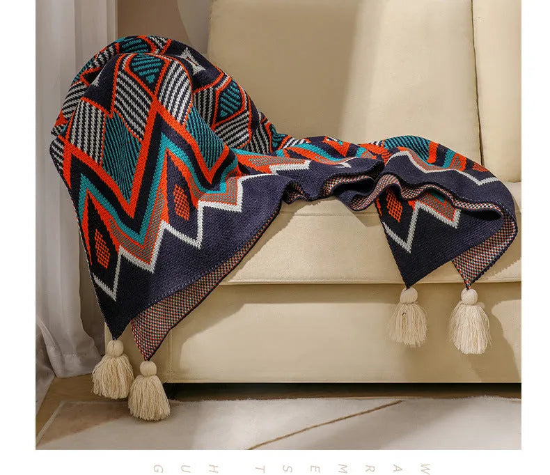 Bohemian style acrylic blanket with tassel fringe on a sofa, shown in a geometric print colour.