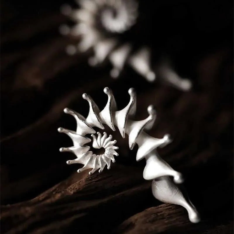 Close-up of a pair of matte-finish, three-dimensional conch shell stud earrings.