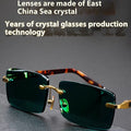 Dark green frameless crystal sunglasses inside a hard case with a cleaning cloth.