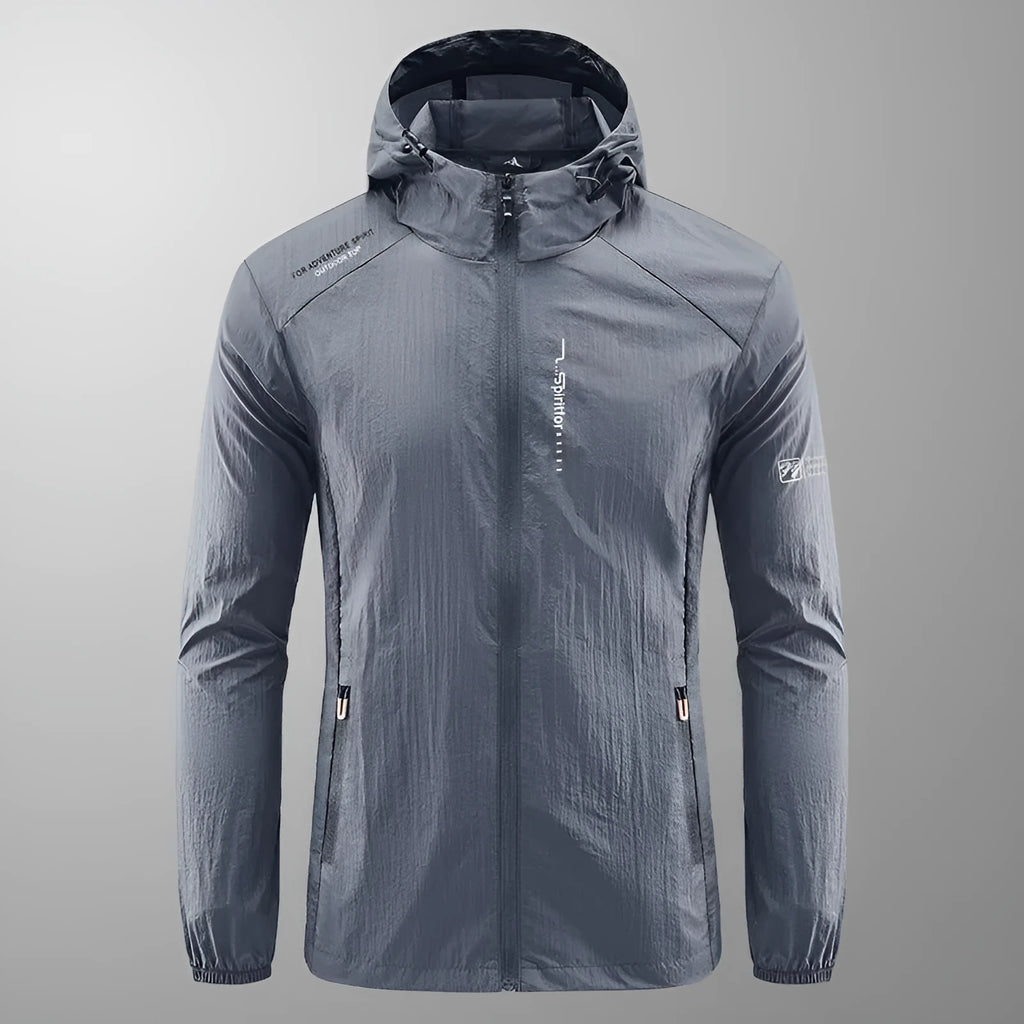 Man wearing a lightweight grey hooded nylon summer jacket outdoors.