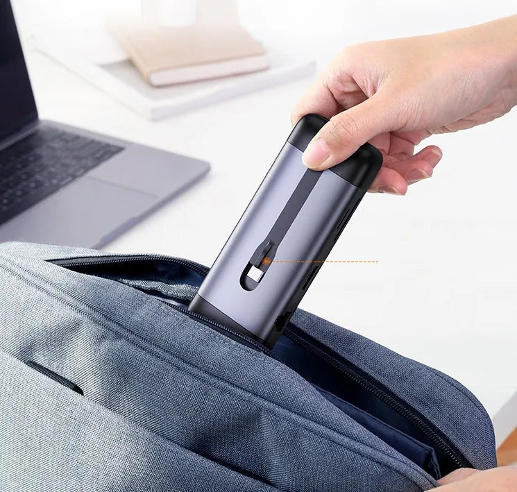 USB-C multi-port expansion dock showing HDMI, VGA, USB 3.0, Ethernet, and card reader ports with connected cables.