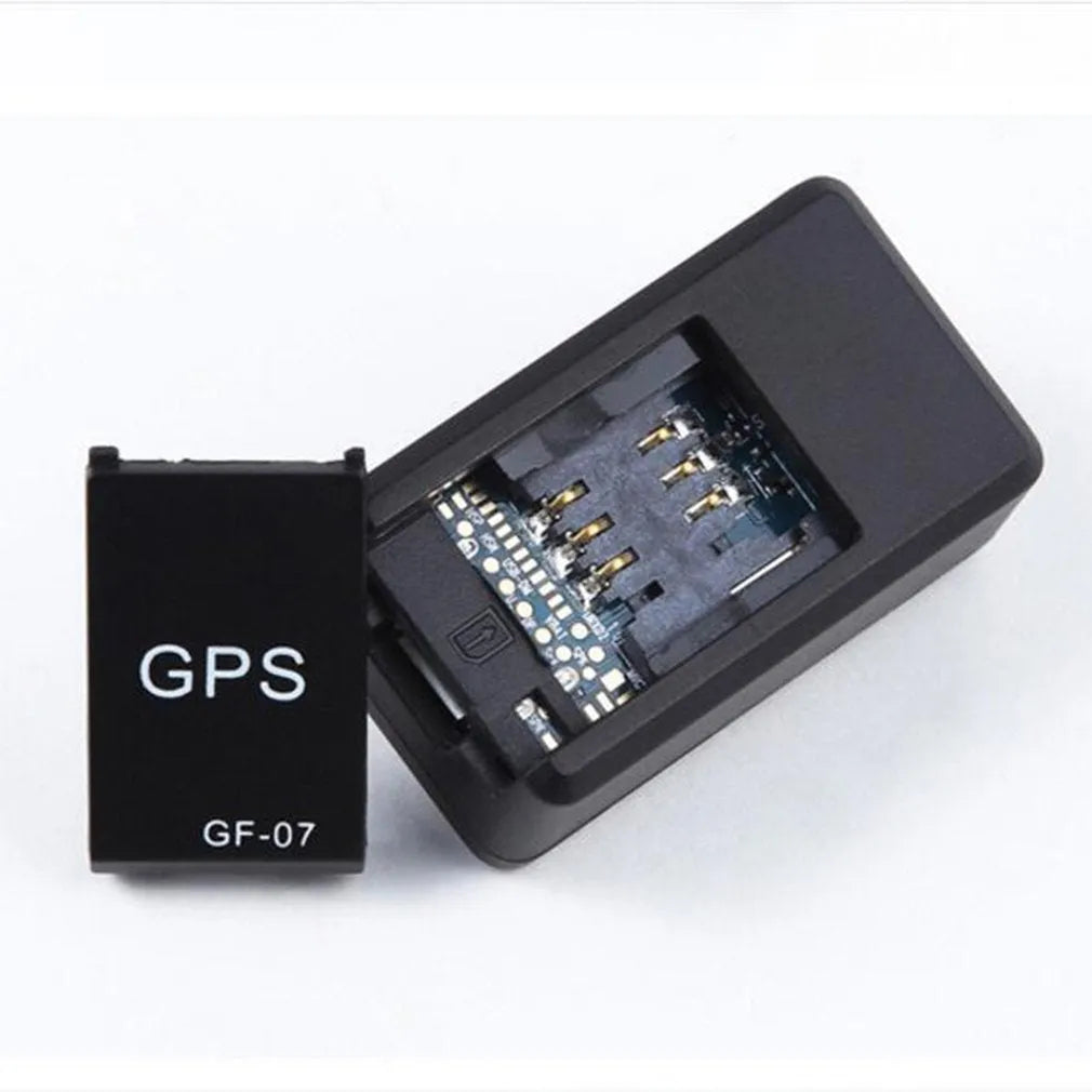 Black mini magnetic GPS tracker next to USB charging cable on a dark surface.