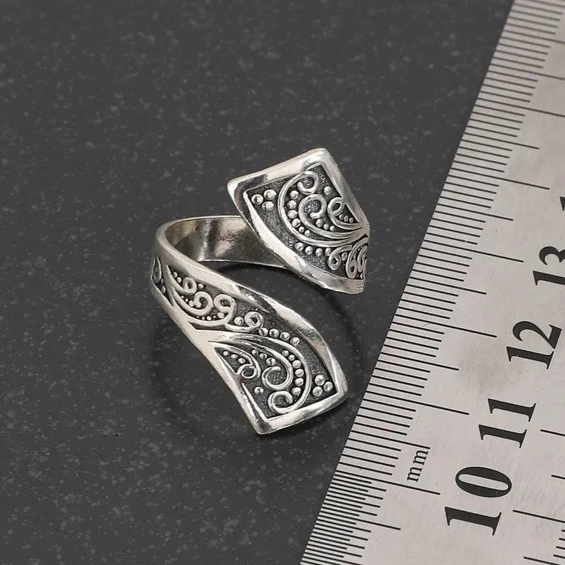 Silver-coloured adjustable opening women's ring with a retro minimalist style on a grey background.