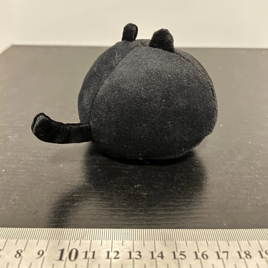 Fluffy black cat stuffed toy with embroidered eyes and whiskers on a grey background.