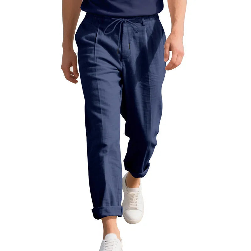 Men's light beige linen casual trousers with a drawstring waist and straight leg on a hanger.