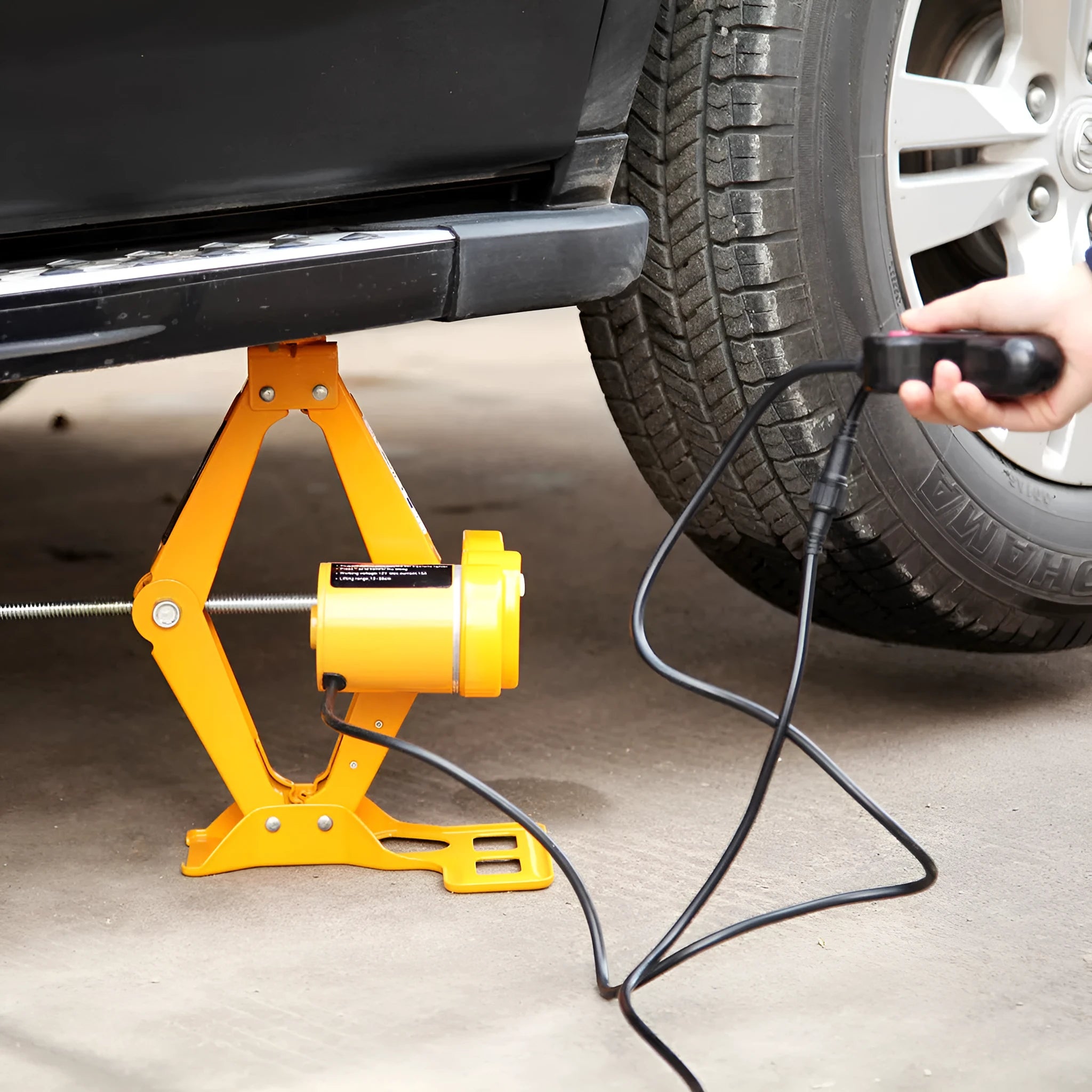 Electric hydraulic car jack kit with 2 tonne lifting capacity mounted in a vehicle boot.