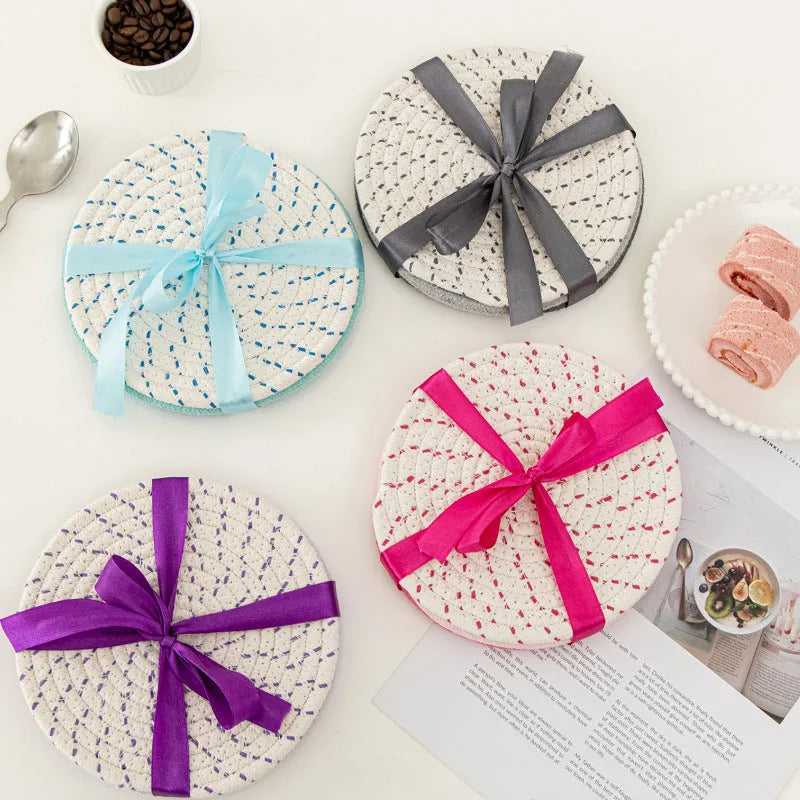 Set of three round grey cotton cord coaster placemats on a wooden table