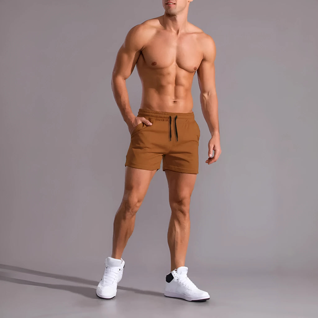 Three pairs of men's solid colour loose fit drawstring shorts in black, khaki, and light brown laid flat