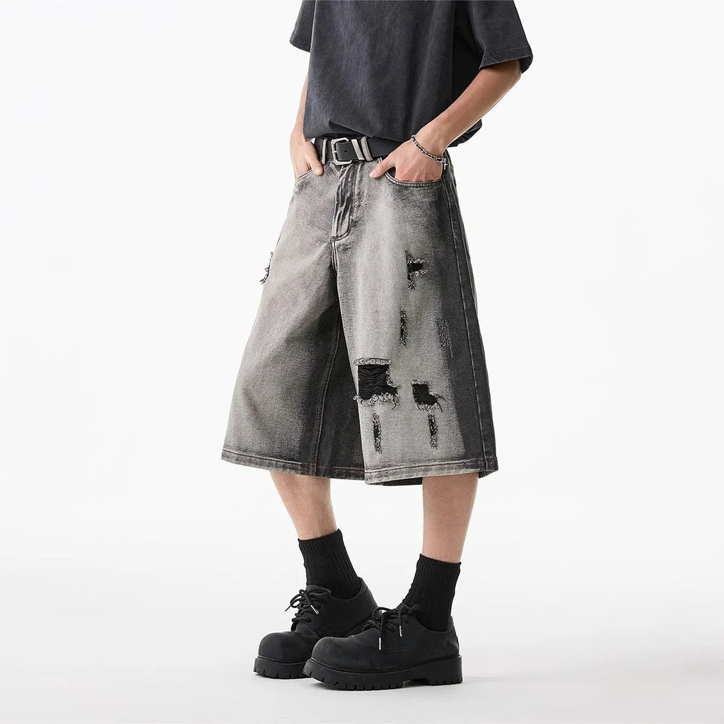 Grey women's denim shorts with distressed hole details and a loose, cropped fit