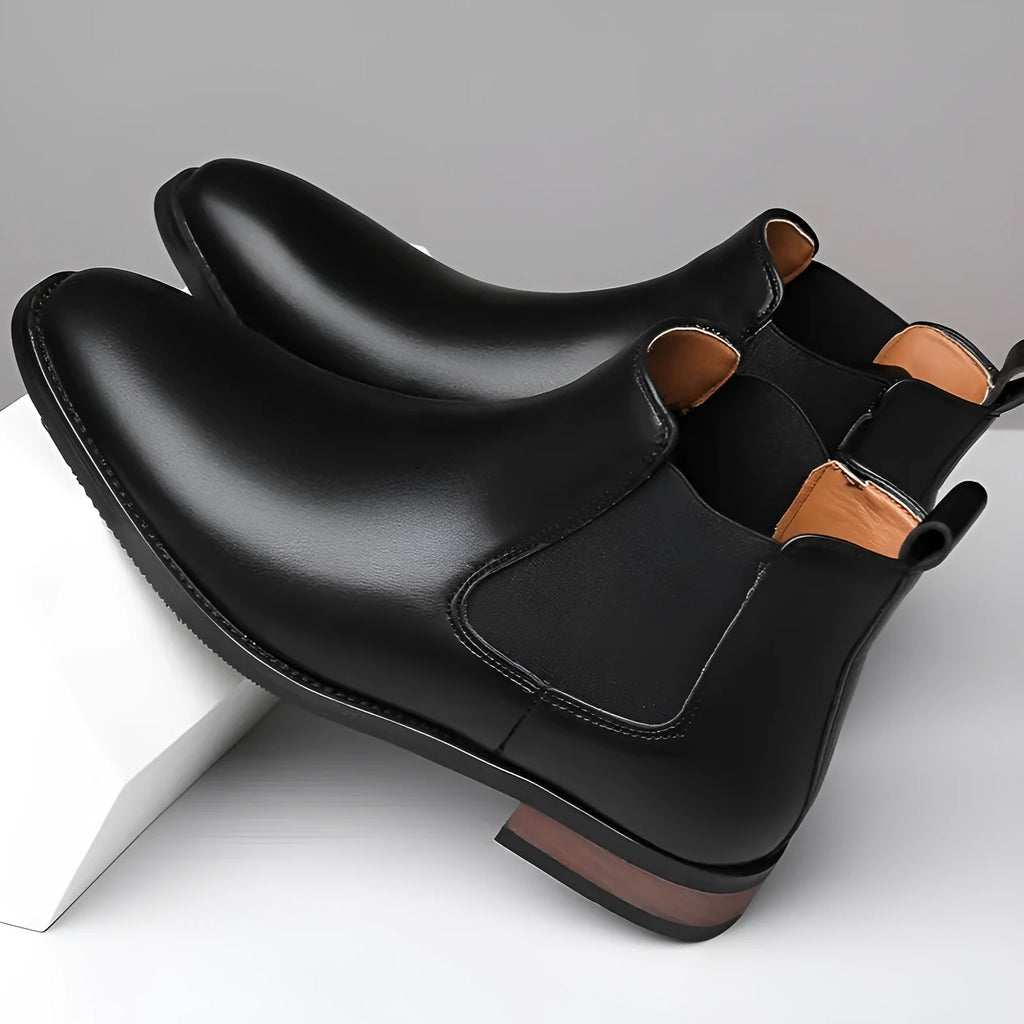 Men's black pointed toe Chelsea boots with a mid-calf height and rubber sole.