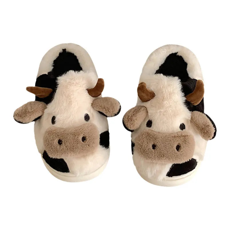 White cow-patterned plush slippers for women with a non-slip textured sole on a wooden floor