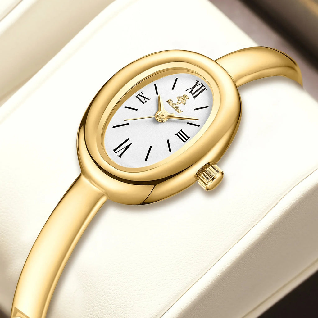 Women's gold and silver oval retro quartz watch with spiral pattern dial on wrist.